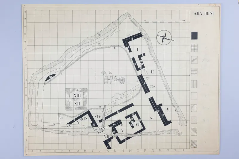 Plan drawing of Ayia Irini on a lettered and numbered grid, with walls shown in solid black, a scale bar and a compass rose.