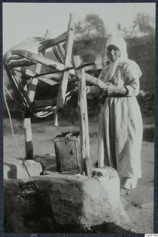 Woman in a white headscarf beside a well with a wooden windlass, Karpas peninsula