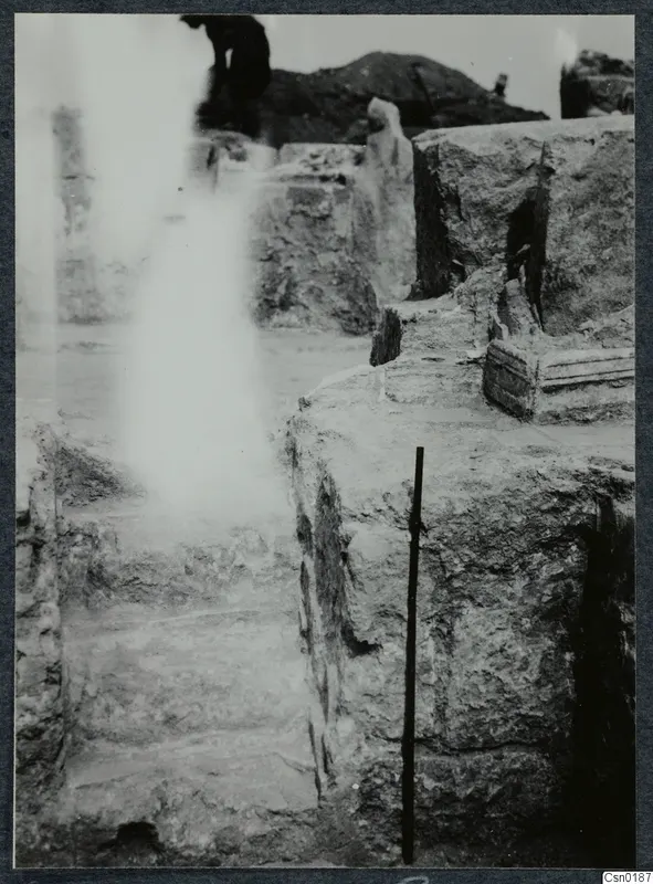 Wall and stairs at Salamis, with a ranging pole against the stonework and a partly visible person behind.