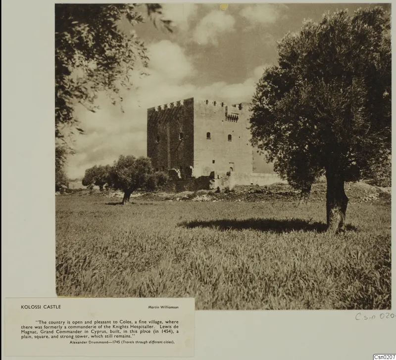 Kolossi castle, a square stone tower with a crenellated top, set among olive trees over a grassy field