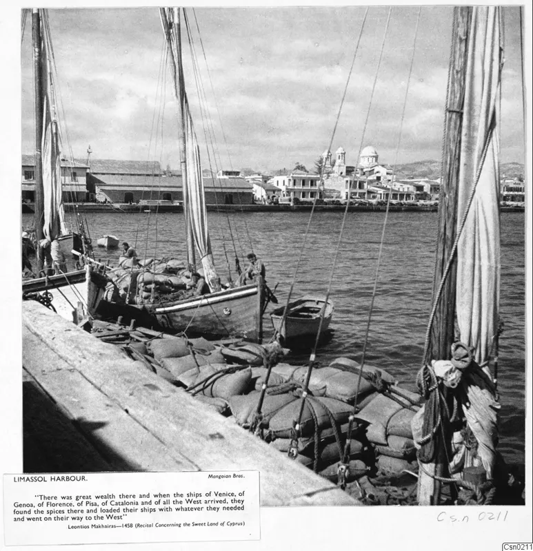 Limassol harbour with sacks stacked on the quay beside moored sailing boats and a waterfront of buildings and a domed church