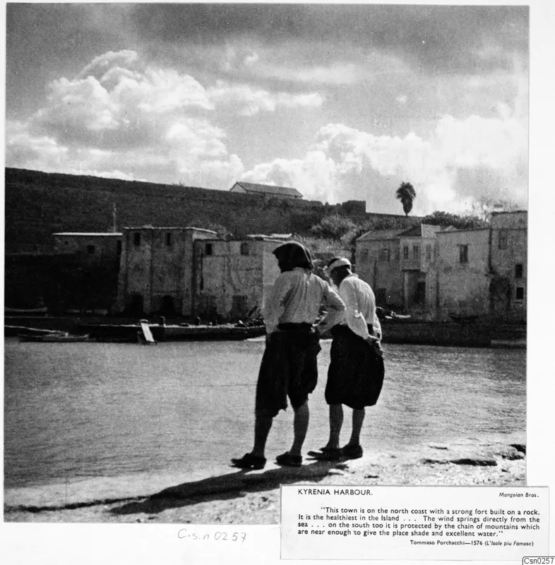 Kyrenia harbour, with two people standing on the rocky shore looking out over the water