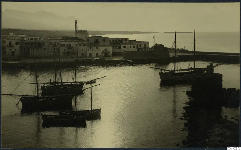 Harbour with whitewashed buildings, moored sailing boats and calm water seen from above