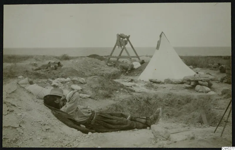 Workmen resting in the excavation at the palace at Vouni, with a white tent and the sea on the horizon.