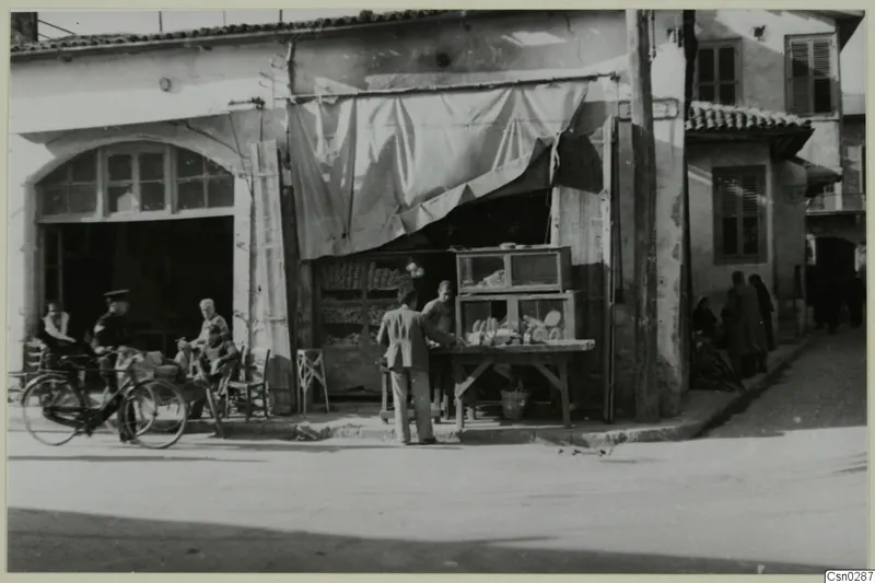 Street corner in Nicosia with a shop front, a bicycle and several people