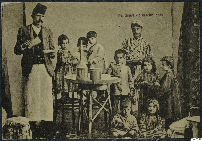 Posed studio group of two men and several children around a small round table with a glass bottle and a tin cup.