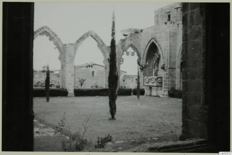 Ruined monastery at Bellapais with pointed arches and tall cypress trees around a grassy courtyard