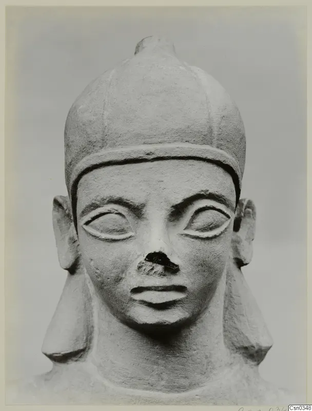 Limestone Neo-Cypriote head, front view, with a tall rounded cap, almond eyes and a broken nose