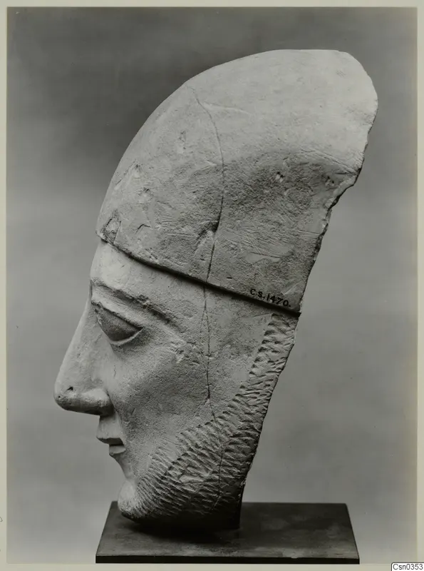 Limestone Neo-Cypriote head of a bearded figure in side view, wearing a tall headdress, on a dark stand