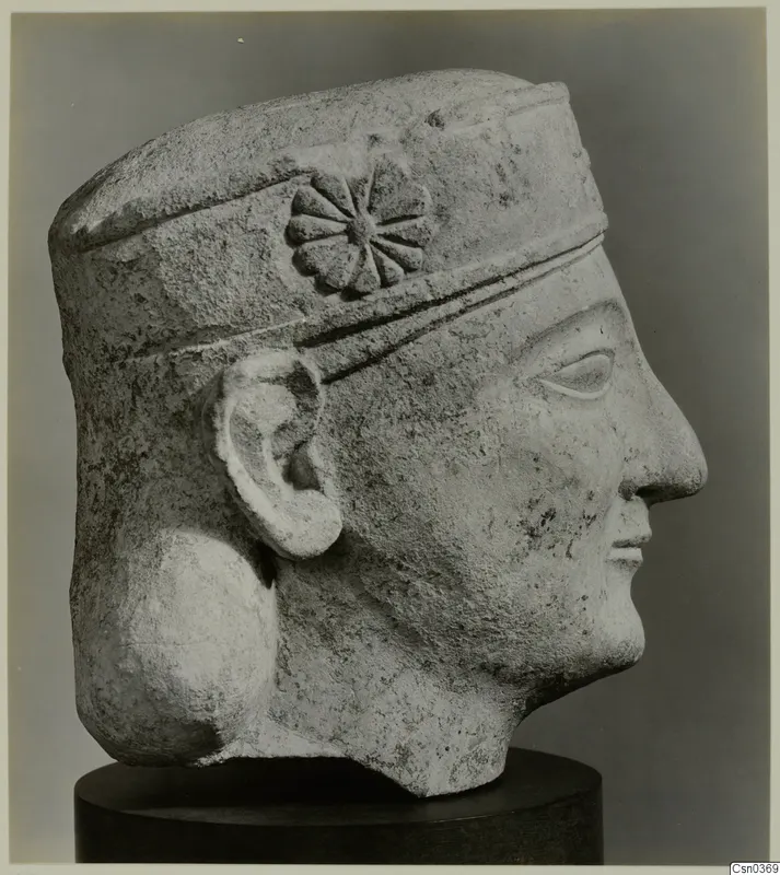 Limestone Neo-Cypriote head in right profile, with a rosette on its headband, on a dark cylindrical stand