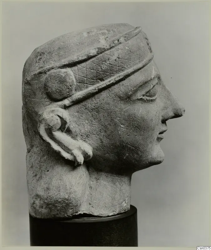 Limestone Neo-Cypriote head in right-facing profile with an incised diamond-patterned band and a spiral ear ornament
