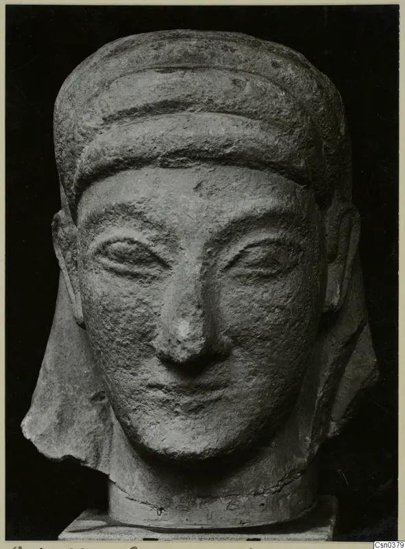 Front view of a limestone sculpted head with a banded headdress, against a black background