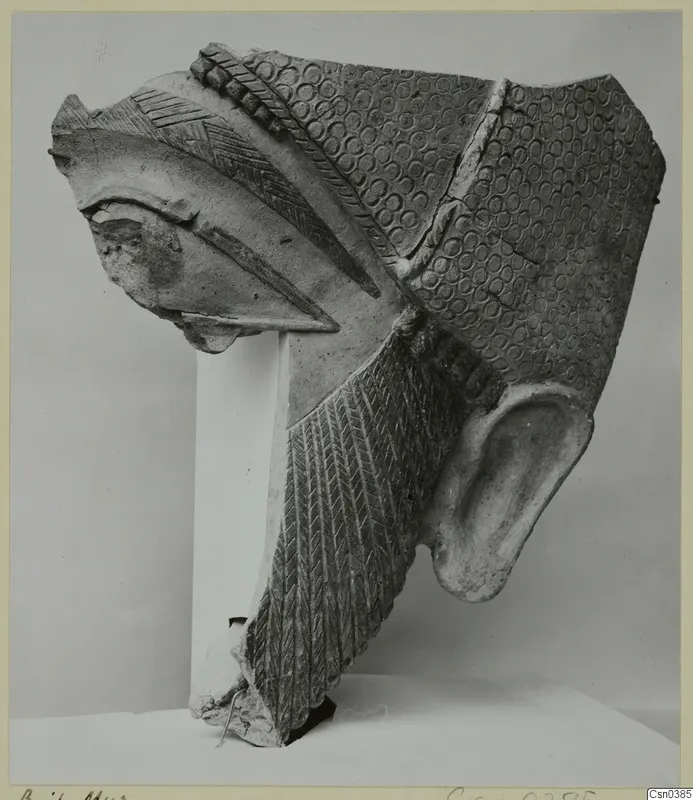 Terracotta Neo-Cypriote statue fragment with a large ear, a beak-like projection and stamped circle patterns.