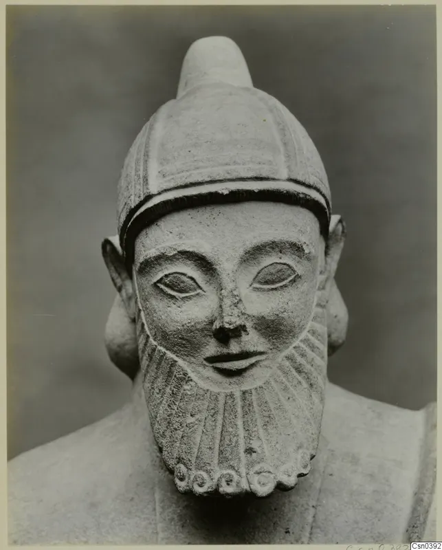 Limestone sculpture of a bearded head wearing a close-fitting cap, facing the camera