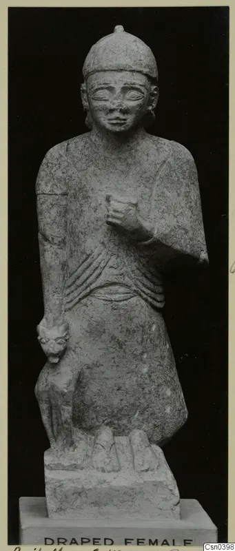 Limestone statue of a standing female figure with a small carved animal beside her, on a rectangular base