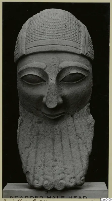 Limestone sculpture of a bearded male head on a plinth, seen from the front