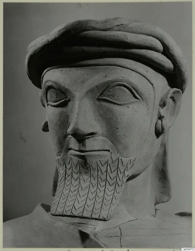 Terracotta bust of a bearded man in a thick rolled cap, with an incised pattern on the beard