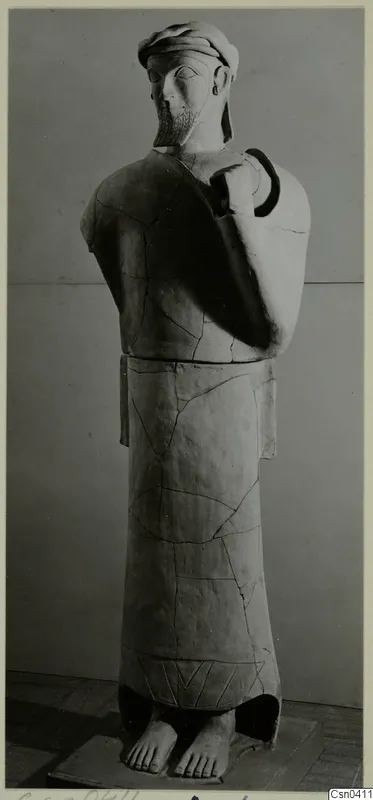 Terracotta statue of a bearded standing male figure with one arm bent up across the chest