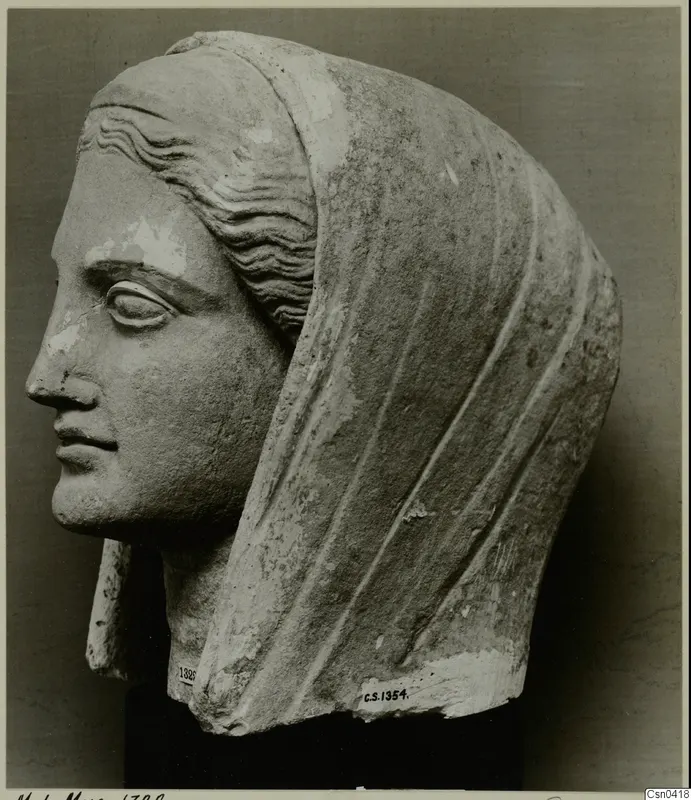 Limestone head with a veil drawn over the back, shown in left profile, with the face and surface partly worn.
