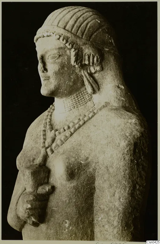 Limestone statue of a figure with ridged hair, a bead necklace and one arm bent at the waist