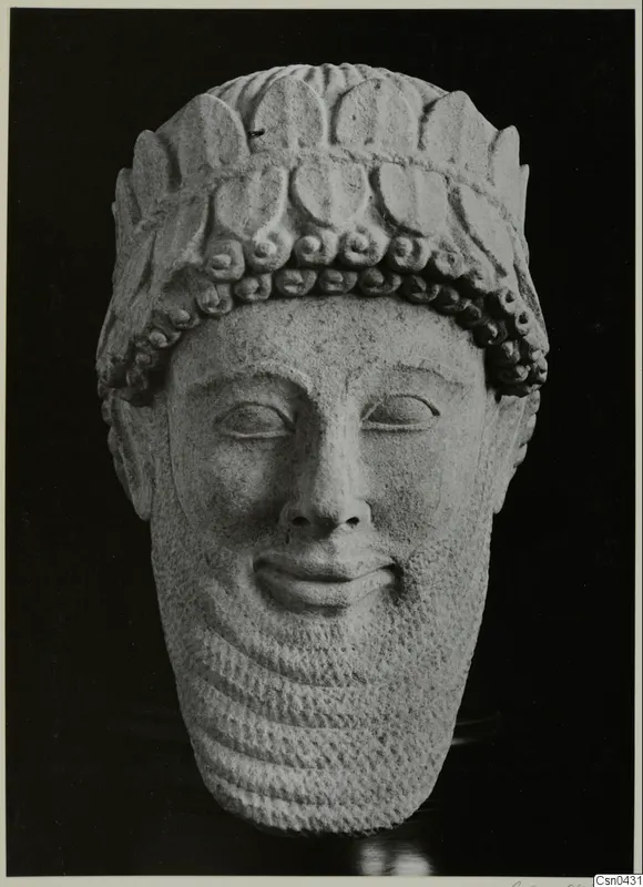 Limestone head of a bearded male figure with a curled hair band, photographed against a black background.
