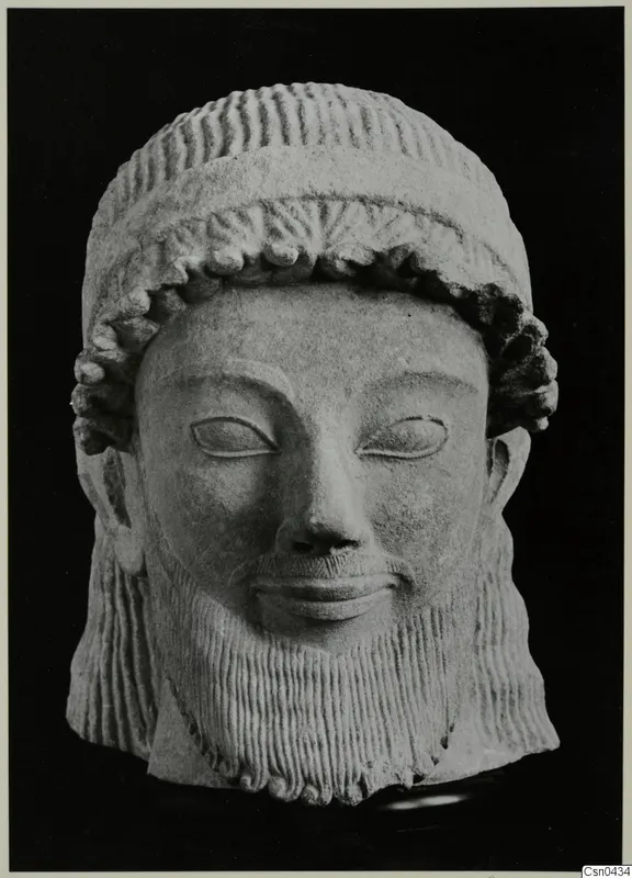 Limestone head of a bearded male sculpture with a wrapped headdress and carved curled hair and beard.