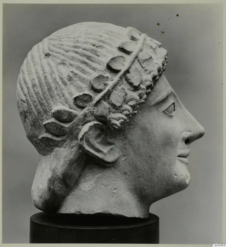 Limestone head sculpture in profile, with carved hair and a wreath or band of leaves over the forehead and ear.