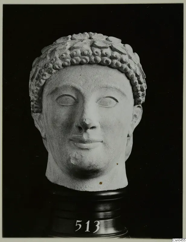 Limestone head with a band of curled hair, photographed against a black background on a dark stand.