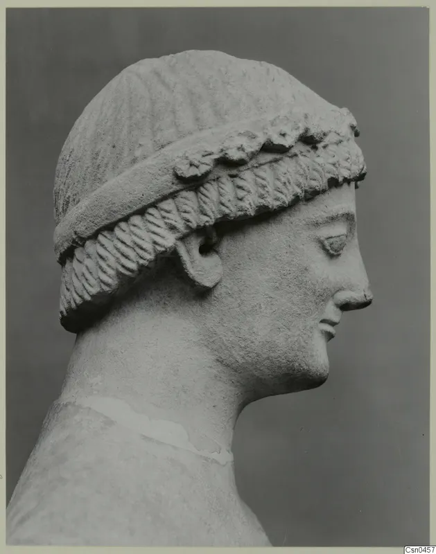 Limestone head in profile, facing right, with a patterned band across the hair