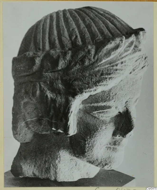 Limestone head of a figure from Mersinaki, shown in side view on a dark stand.