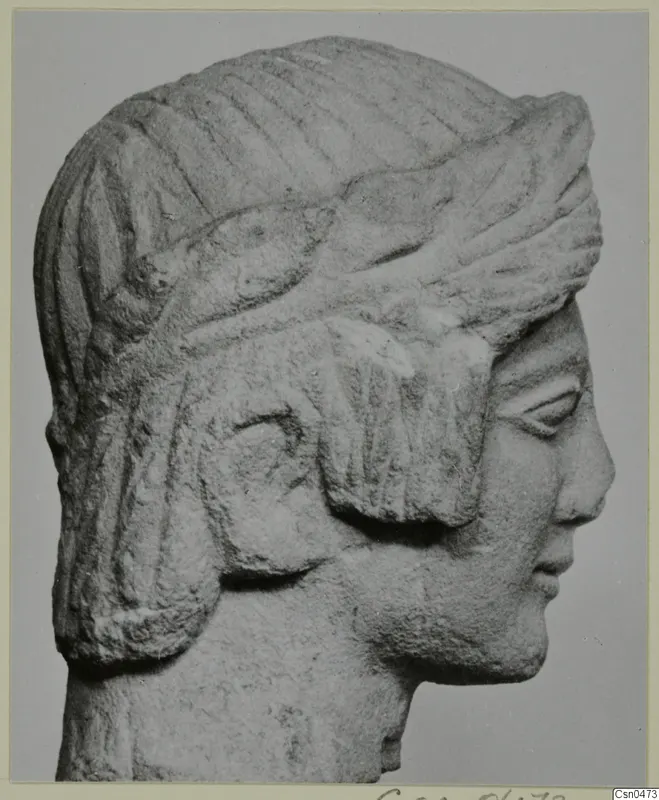 Limestone head in profile facing right, with a band across the hair and locks falling over the ear.