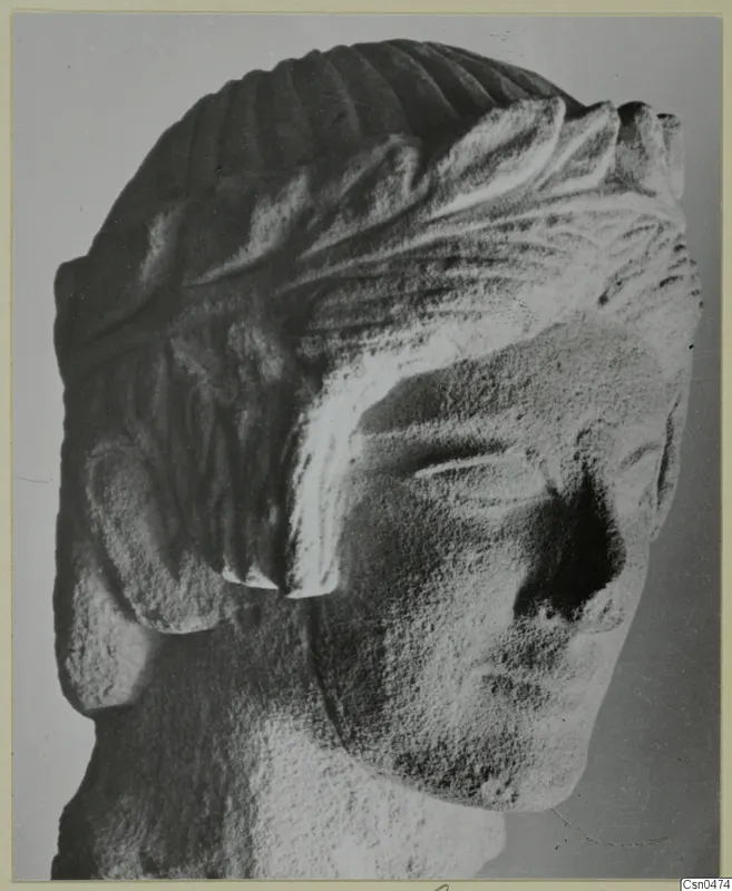 Limestone head from Mersinaki with carved, ridged hair and a broken nose.