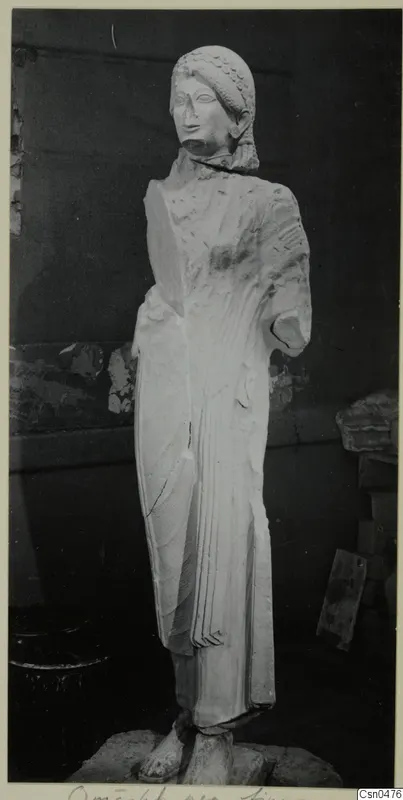 Limestone statue of a standing woman from Vouni, photographed against a dark wall.