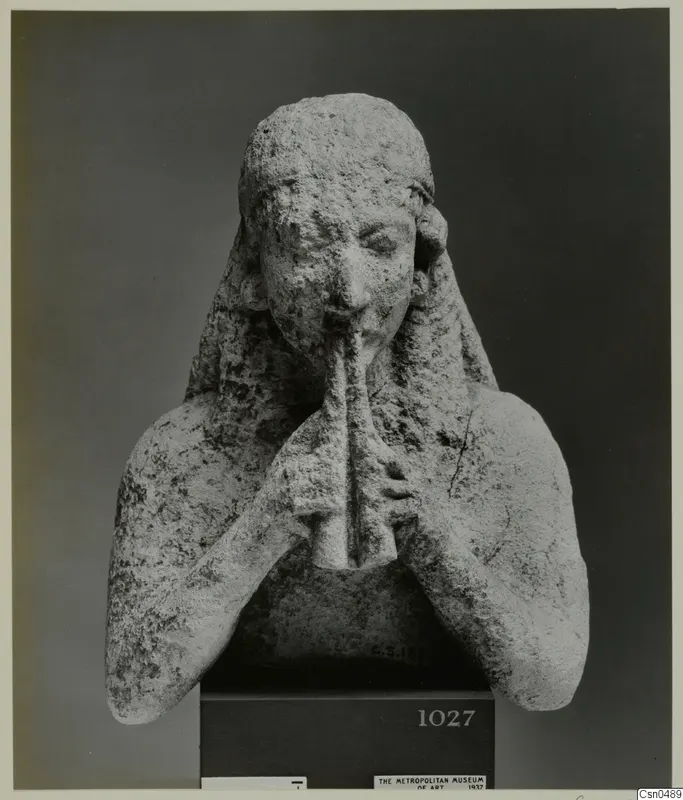 Limestone bust of a figure with both hands raised to a pipe-like instrument at the mouth