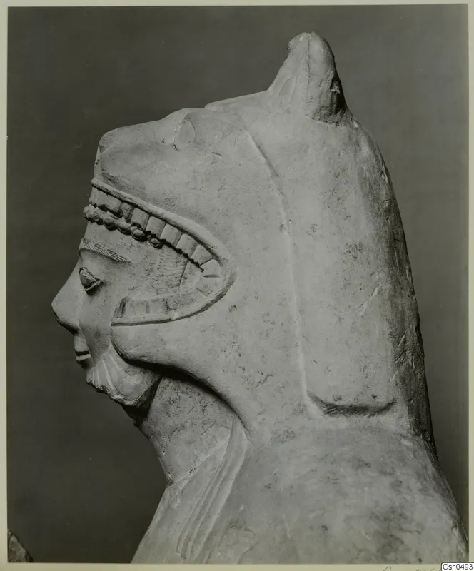 Limestone sculpture of a head in profile, with a tall headdress and a carved band of beads and notches across the brow