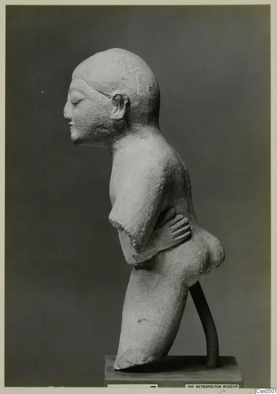 Limestone sculpture of a figure in profile, one hand resting on its waist, on a dark base