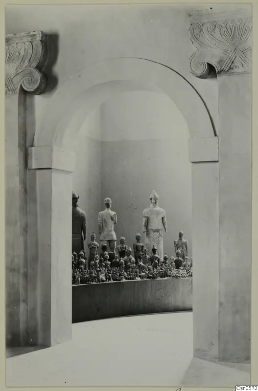 Statues and small figurines displayed on a curved plinth inside an arched recess, Cyprus Museum
