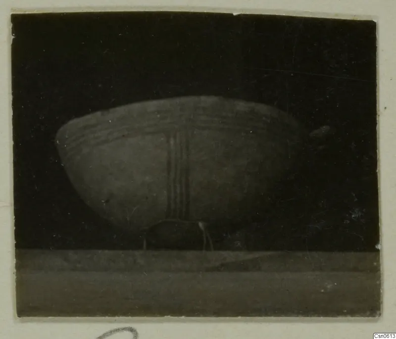 Pottery bowl with horizontal bands and three vertical stripes painted on its body, shown against a dark background.