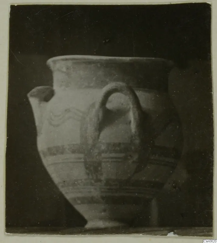 Pottery vessel with a loop handle, a spout and painted bands, shown against a dark background