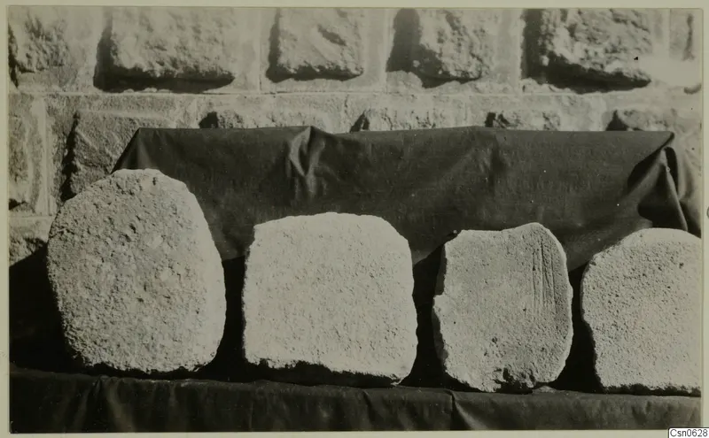 Four rough stone blocks set in a row on a dark cloth, stones from Kalopsidha