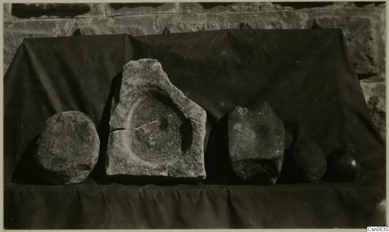Five stone pieces from Alambra on a dark draped cloth, one with a circular hollow in its upper face