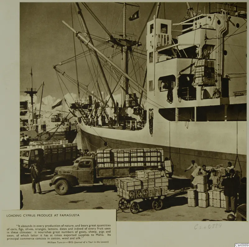 Wooden crates being loaded from a quay onto a lorry and a cart beside a cargo ship at Famagusta