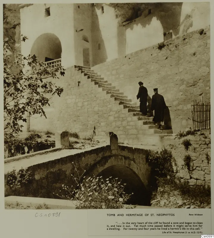 Stone steps up to a whitewashed building with an arched doorway, two robed men climbing, at the hermitage of St. Neophytos