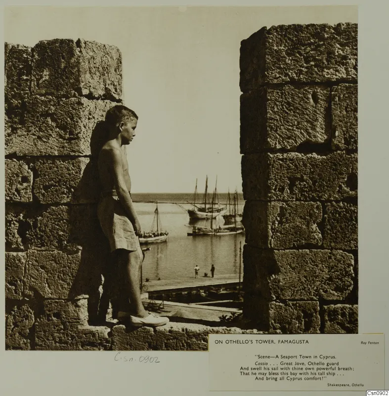 Boy leaning on the stone wall of Othello's Tower, Famagusta, looking out over the harbour with sailing boats