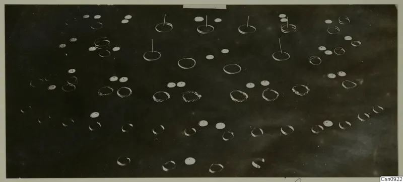 Scattered jewellery on a dark background: plain rings, twisted spiral bands and flat discs with holes