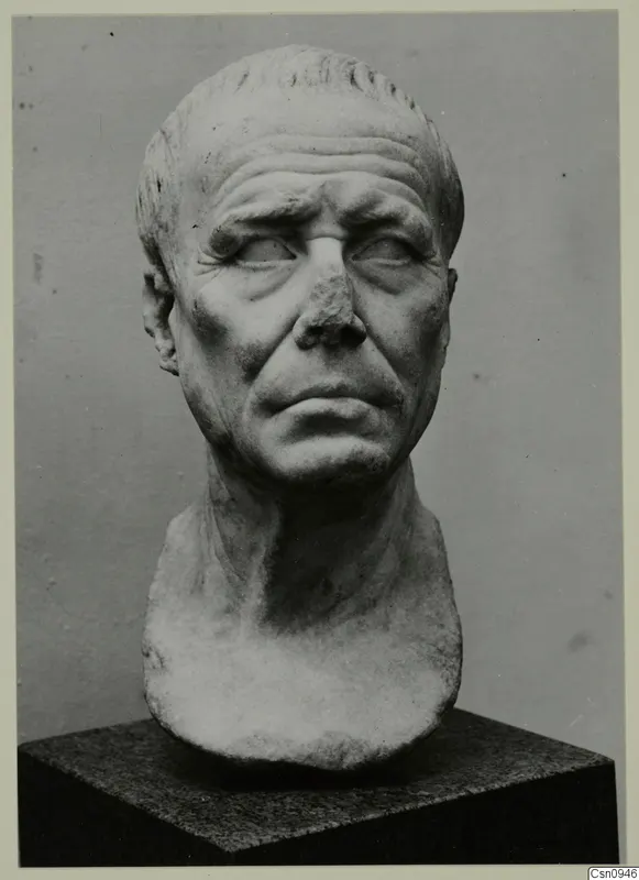Marble portrait head of an older man with a bald crown, creased brow and broken nose, on a dark stone base.