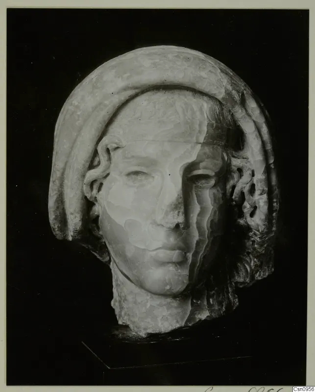 Carved stone head of a figure with a smooth, close-fitting band over the hair, photographed against a black background.