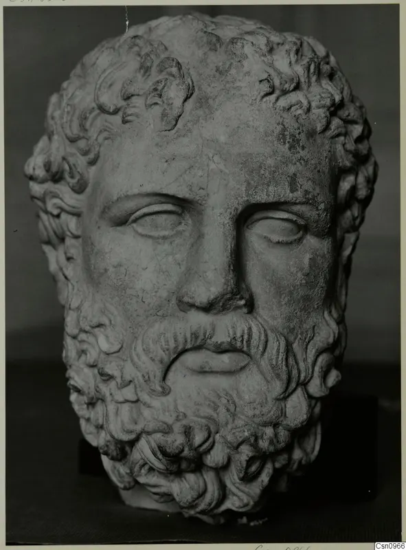 Bearded male head sculpture in stone, with wavy hair and beard and downcast eyes.