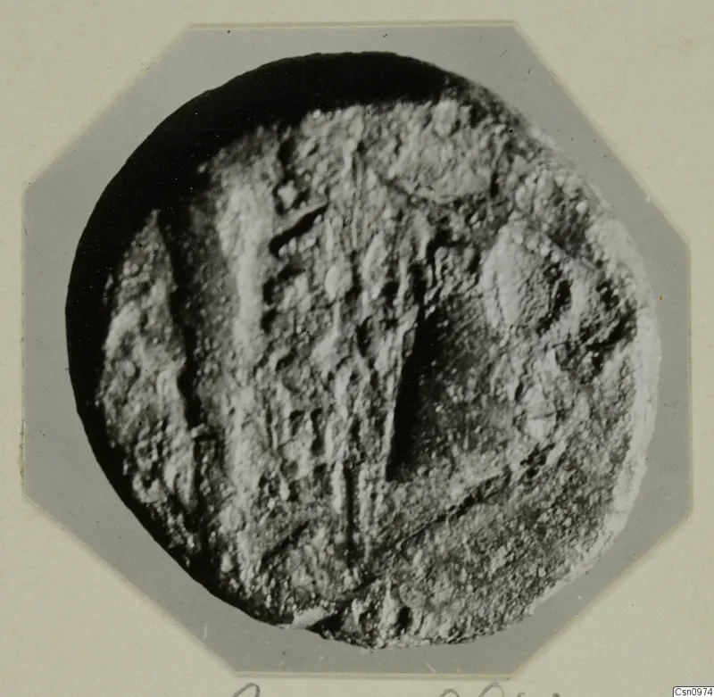 Round find with a raised, ridged pattern, photographed on an octagonal card mount, from Kountoura Trachonia