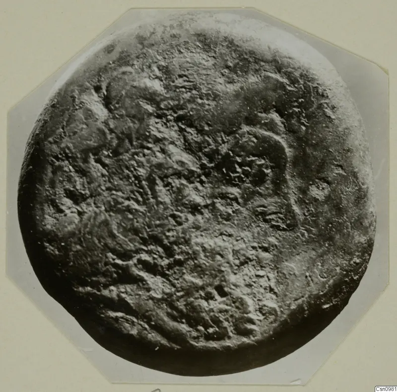 Heavily corroded round find from Kountoura Trachonia, photographed close up on a mount